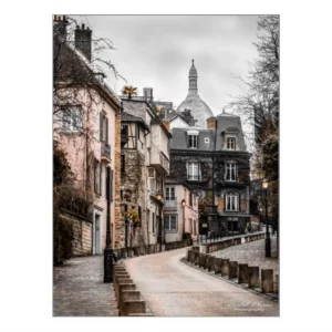 Rue pavée sinueuse à Montmartre, Paris, avec le dôme du Sacré-Cœur en arrière-plan.