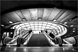 Escalier moderne sous une verrière avec des silhouettes en mouvement